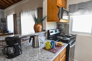 Une cuisine équipée de plans de travail en granit, d’une machine à café, d’une bouilloire et d’un four à micro-ondes.