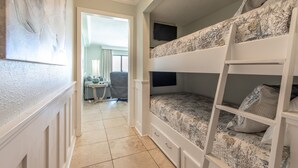 Una habitación con literas, un televisor montado en la pared y un escritorio con una silla.