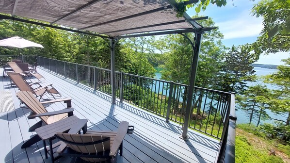 A covered deck with outdoor seating and a view of a lake.