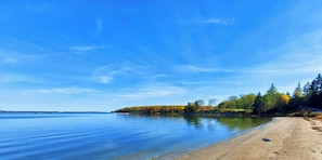 A beach with a clear sky and calm water. Text indicates Reach Beach, Deer Isle, located 5 miles from rental property. - Waterfront Home with Expansive 50-Foot Deck and Stunning Water Views (Deer Isle)