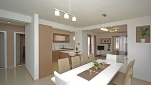 A modern living room with a dining area, a kitchen, and a TV.