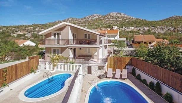 A two-story house with a swimming pool and a balcony.