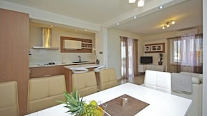 A modern living room with a dining area, a kitchen, and a seating area with a TV.