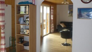 Un salón amplio con una estantería de madera, una mesa de comedor y una silla negra.