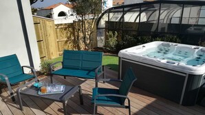 Una terraza con un jacuzzi, dos sillas turquesa y una mesa con una bandeja de bebidas.