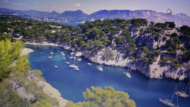 A coastal landscape with rocky terrain and a clear blue sea.