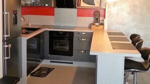 A modern kitchen with a central island, built-in oven, microwave, and a refrigerator.