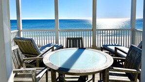 A covered outdoor seating area with a glass table and chairs, overlooking a beach with the ocean. - Beachfront in Seaside on Double Lot, Amazing Gulf views, sleeps 4 + 2 Bikes! (Santa Rosa Beach)