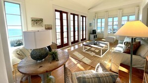 A spacious living room with a large window overlooking the sea, a ceiling fan, and a cozy seating area with a sofa and chairs. - Beachfront in Seaside on Double Lot, Amazing Gulf views, sleeps 4 + 2 Bikes! (Santa Rosa Beach)