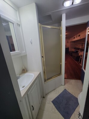 Une petite salle de bain comprenant un lavabo, un miroir et une douche.