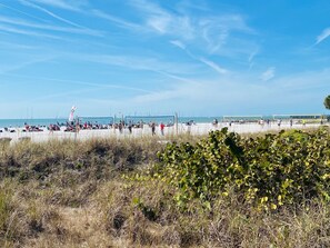 Een strand met mensen, een volleybalnet en een vlag.
