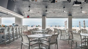 An outdoor seating area with tables and chairs, overlooking a beach. - Beach Vacay With View! Direct Beach Access, Pool, Bar, Restaurant! (Fort Myers Beach)