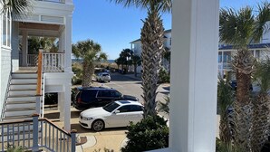 A residential street with a white house, a covered porch, and parked cars. - Beautifully updated cottage with ocean views, only steps to the beach! (Wrightsville Beach)
