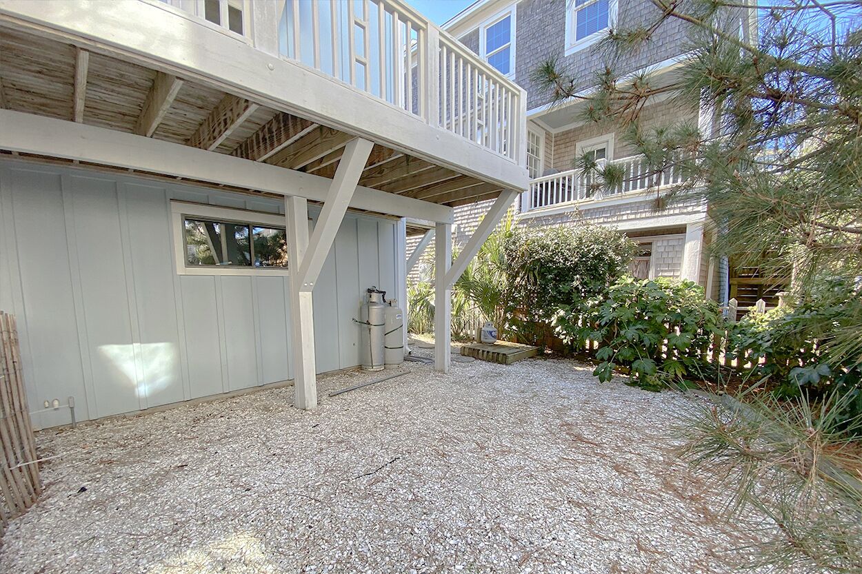 A two-story building with a covered deck and a gravel driveway.