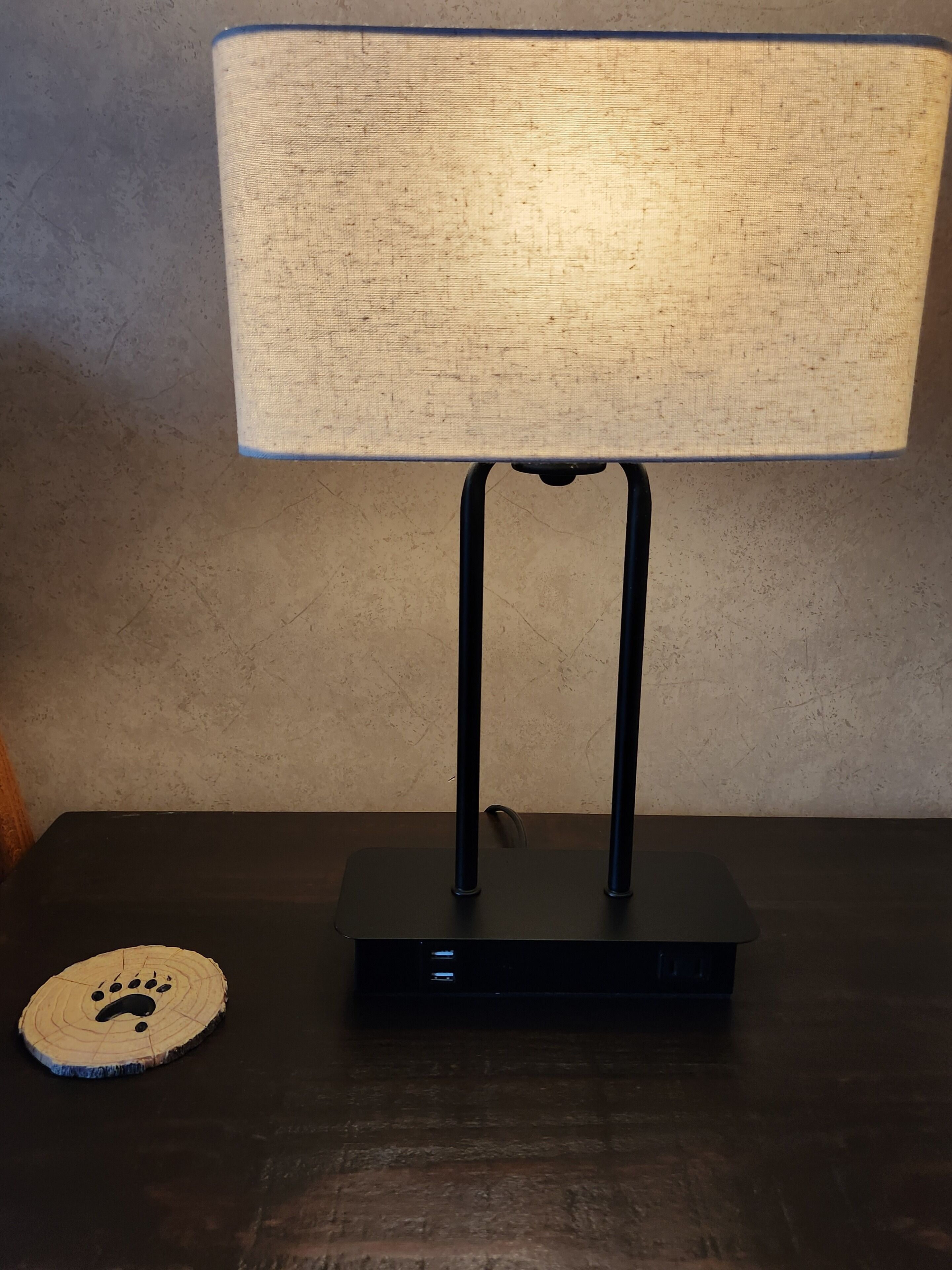 Een tafel met een lamp en een onderzetter.