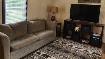 A living room with a sofa, a patterned rug, a television, and a lamp.