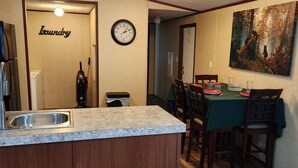 Una cocina con encimera de granito, dos taburetes de bar, un lavamanos y un reloj en la pared.