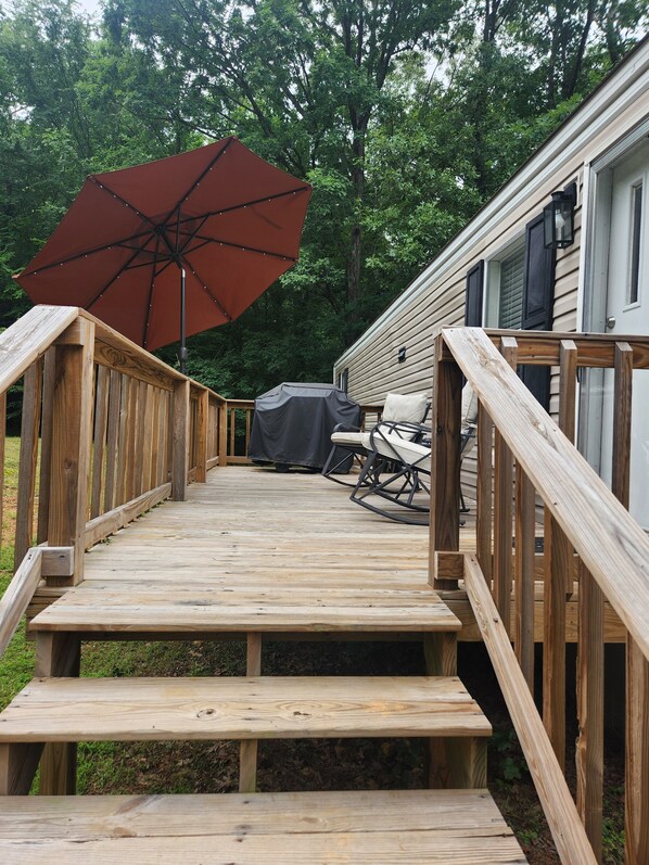 A wooden deck with a covered seating area, a barbecue grill, and a large umbrella.