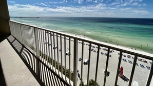 Ein Balkon mit Blick auf einen Strand, einen Pier in der Ferne und strahlend klarem Himmel.
