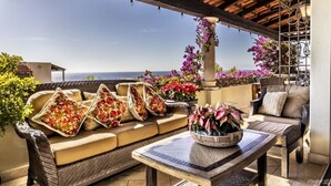 Eine Terrasse mit einer Couch, Stühlen und einem Tisch mit Blick auf eine schöne Landschaft.