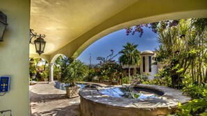 A courtyard with a stone fountain, potted plants, and a building with columns. - Arch/Lands End Oceanviews - 4200 sq ft Luxury Villa, Private Beach (Cabo Bello)