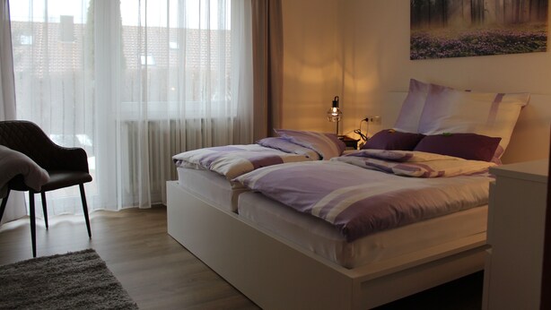 Ein Schlafzimmer mit einem Bett, einem Sessel und einem Bild an der Wand.