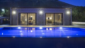 A modern house with a swimming pool, large glass doors, and a mountain backdrop. - Casa Assisi with private pool & sea view (Kefalonia)