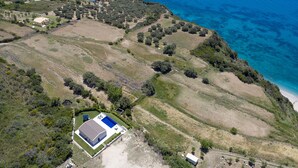 An aerial view of a coastal property with a large house, a swimming pool, and a beach. - Casa Assisi with private pool & sea view (Kefalonia)