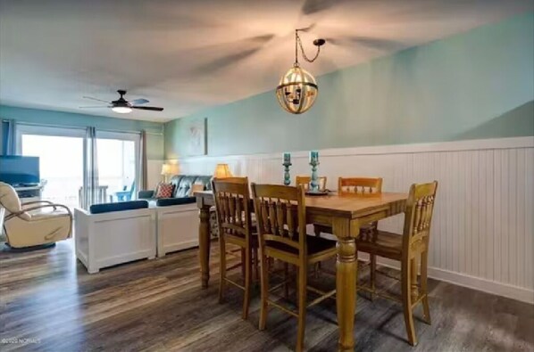 A dining area with a wooden table and chairs, a chandelier, and a ceiling fan. - Ocean & Lake Views. Steps to the Beach. (Carolina Beach)