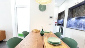 Ein Essbereich mit einem Holztisch, grünen Stühlen, einer gewebten Tischmatte und einer grünen Vase.