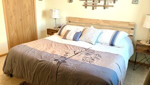Une chambre à coucher comprenant un lit, des tables de chevet, une armoire en bois et des éléments de décoration murale.