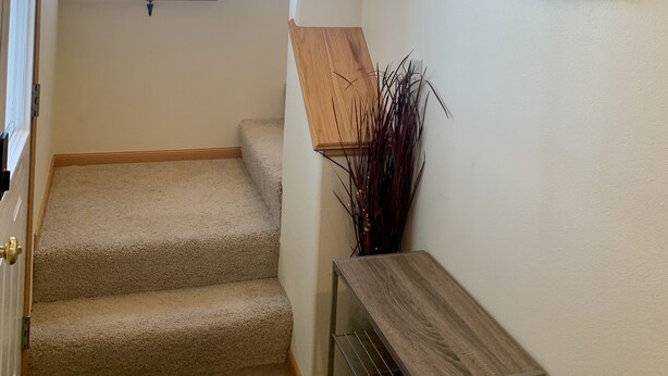 Un escalier avec une rampe en bois, une petite étagère en bois et une plaque fixée au mur portant le numéro 106.