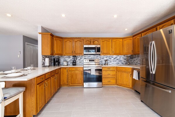 Enjoy cooking in this well-equipped kitchen with a central island, oven, and stainless steel refrigerator.