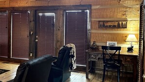 L’intérieur d’un chalet en bois comprend une chambre à coucher située en mezzanine, un coin repas et un salon avec un canapé et des fauteuils.