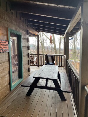 A wooden deck with a picnic table and a sign reading "Welcome Tracks Cabin Short Ridge Ct."