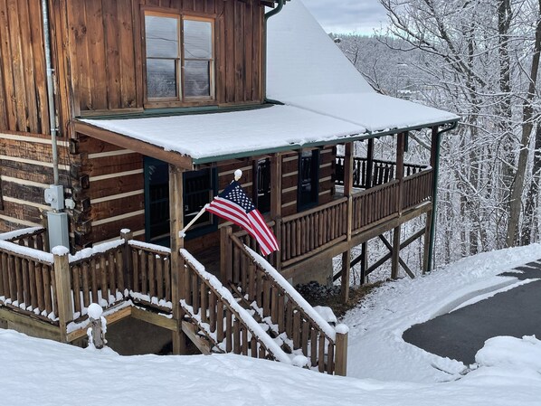 A wooden cabin with a porch and a flag.