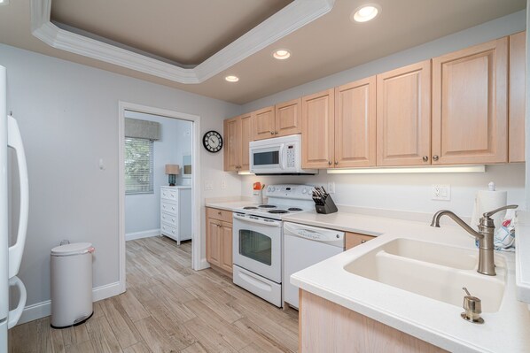 Una cocina moderna con gabinetes de madera, microondas, estufa y pileta.