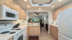 Une cuisine moderne avec des appareils électroménagers blancs, des meubles en bois et un îlot central.