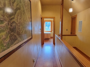 Explore the charming hallway leading to a room with a window offering a view of lush greenery.