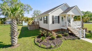 A single-story house with a porch, a small deck, and a landscaped garden with a palm tree. - Beach View Cottage Perfect for Family & Friends! (Gulfport)