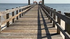 A wooden pier leading to a sign reading "Libby Miller Roland Municipal Pier." - Beach View Cottage Perfect for Family & Friends! (Gulfport)