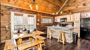 A wooden cabin interior with a kitchen, dining table, and stools. - "New Lake Cabin in an Incredibly Quiet Setting" (Langston)
