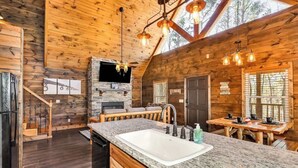 A log cabin interior with a kitchen, dining area, and a stone fireplace. - "New Lake Cabin in an Incredibly Quiet Setting" (Langston)