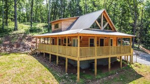 A wooden cabin with a balcony, a pitched roof, and a single-story structure. - "New Lake Cabin in an Incredibly Quiet Setting" (Langston)