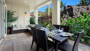 A covered patio with a dining table set for four, surrounded by wicker chairs, and a seating area with a sofa and cushions. - Poipu Kai B111: Lovely Gardenview Villa w/Shared Pool, Spa & AC, Near Beaches (Koloa)