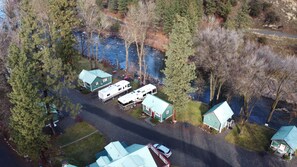 An aerial view of a campground with RVs, a small house, and a boat near a river. - "The Hideaway" - Cabin 3 (New Meadows)