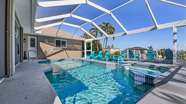 A swimming pool with clear blue water, surrounded by a white geometric canopy and green lounge chairs. - Stunning Waterfront Oasis - Bikes, Kayaks, Pool & Spa, and much more! - Villa X-Ta-Sea - Roelens (Cape Coral)