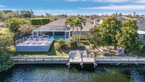 A waterfront property with a covered deck, outdoor seating, and a dock with kayaks. - Stunning Waterfront Oasis - Bikes, Kayaks, Pool & Spa, and much more! - Villa X-Ta-Sea - Roelens (Cape Coral)
