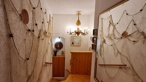 A hallway with wooden walls, a wooden door, a chandelier, and a framed picture on the wall. - Three Mermaids House, Piran (Piran)