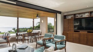 Una sala de estar moderna con un televisor grande, asientos cómodos y vista al océano.